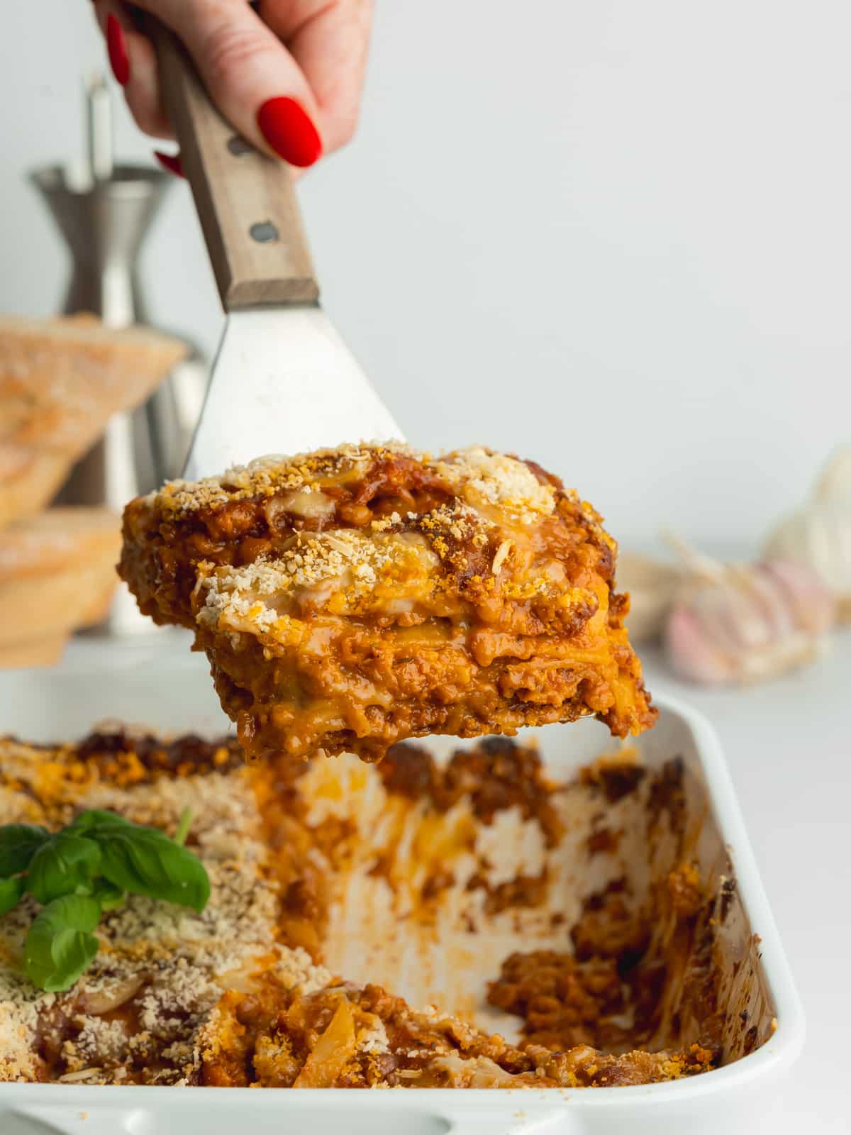 a slice of vegan lasagna being lifted out of a cooking dish.