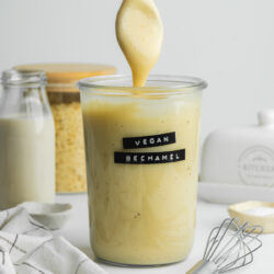 a jar of vegan bechamel with a spoon showing the thick consistency.