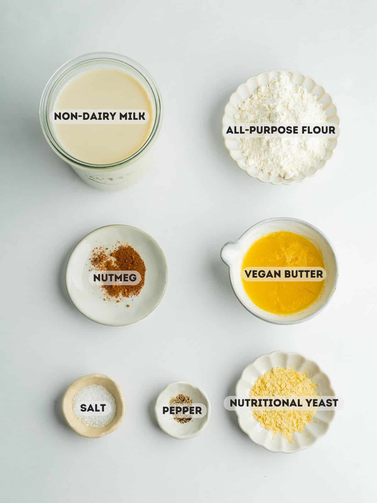 ingredients for vegan bechamel measured in bowls on a gray surface.