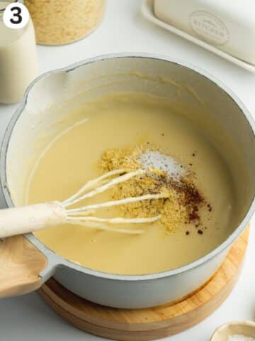 bechamel sauce in a pan with a whisk and seasonings.