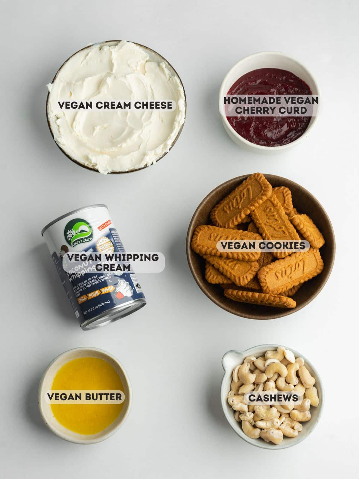 ingredients for cherry cheesecake measured in bowls on a gray surface.