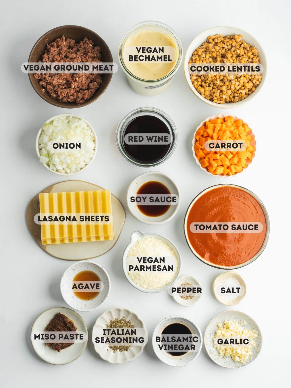 ingredients for vegan lasagne measured in bowls on a gray surface.
