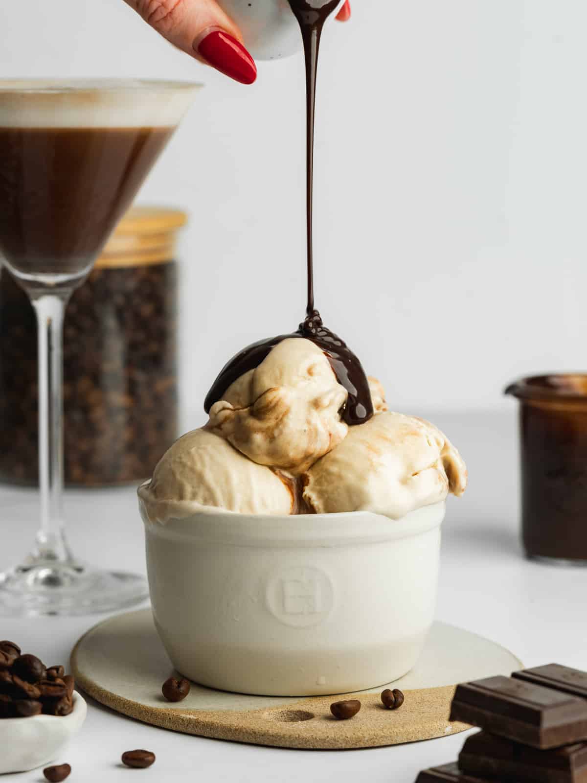 scoops of espresso ice cream in a ramekin with chocolate fudge sauce being poured on top.