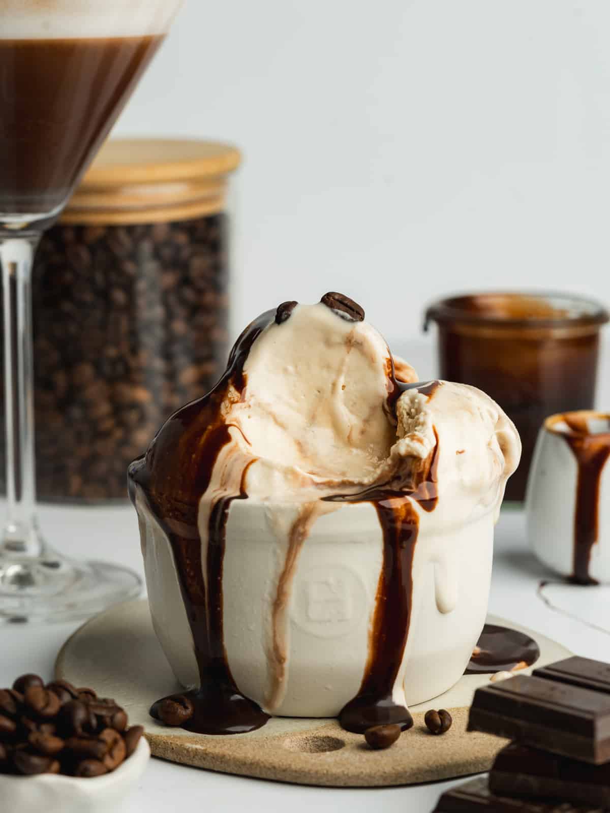 espresso martini ice cream scoops with espresso chocolate fudge sauce in a ramekin and a spoonful taken showing the creamy consistency.