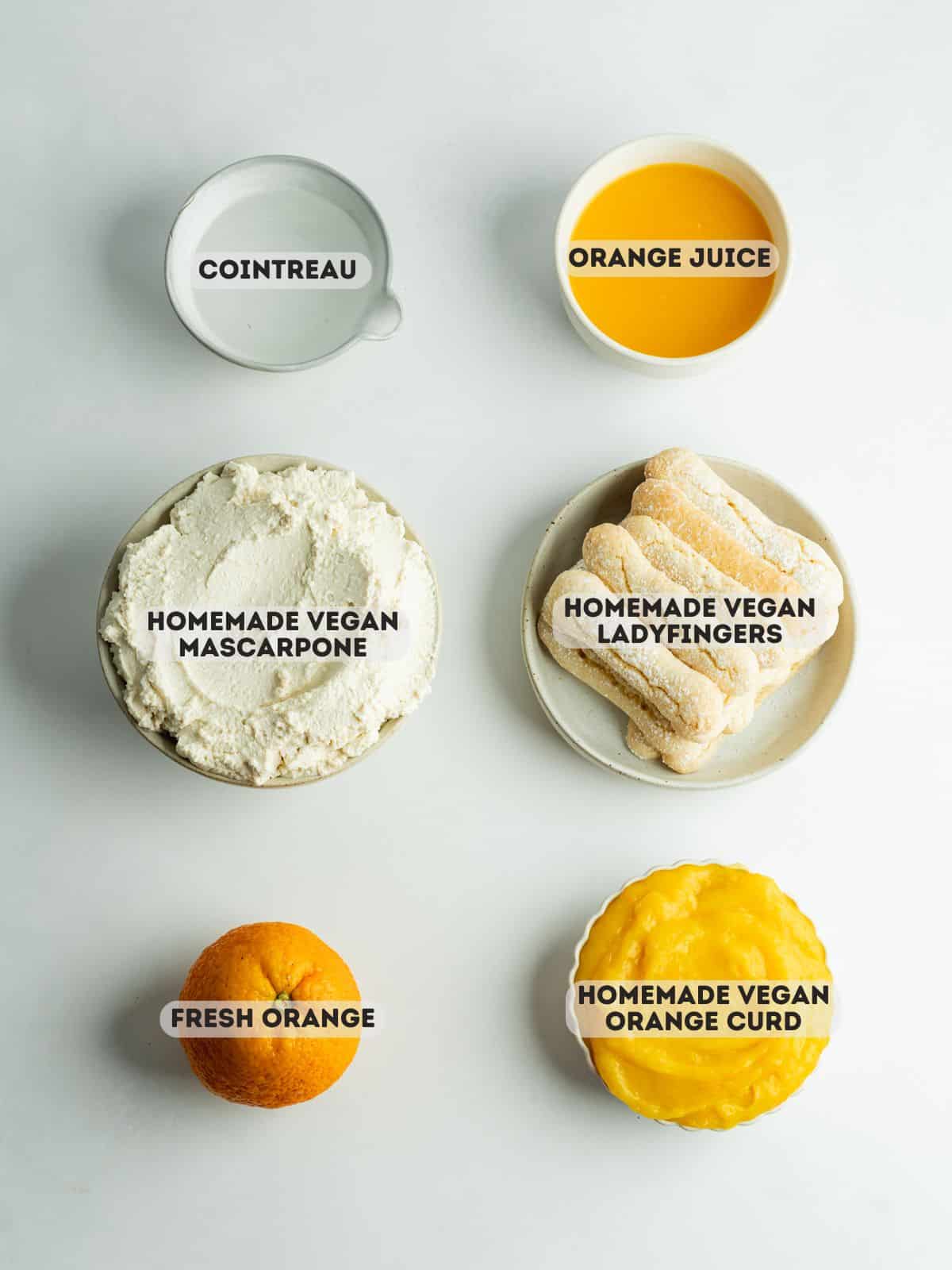 ingredients for orange tiramisu measured out in bowls on a gray surface.