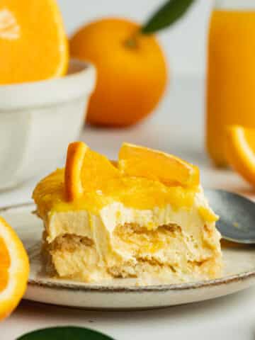 a slice of fresh orange tiramisu with a spoonful taken from it showing the super creamy consistency.