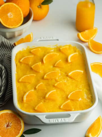 a ceramic staub pan with orange tiramisu topped with orange curd and fresh orange slices.