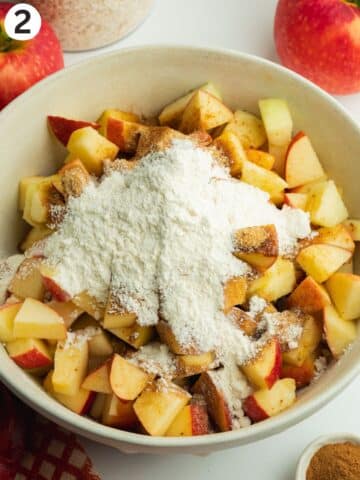 chopped pink apples in a bowl with brown sugar, flour and spices.