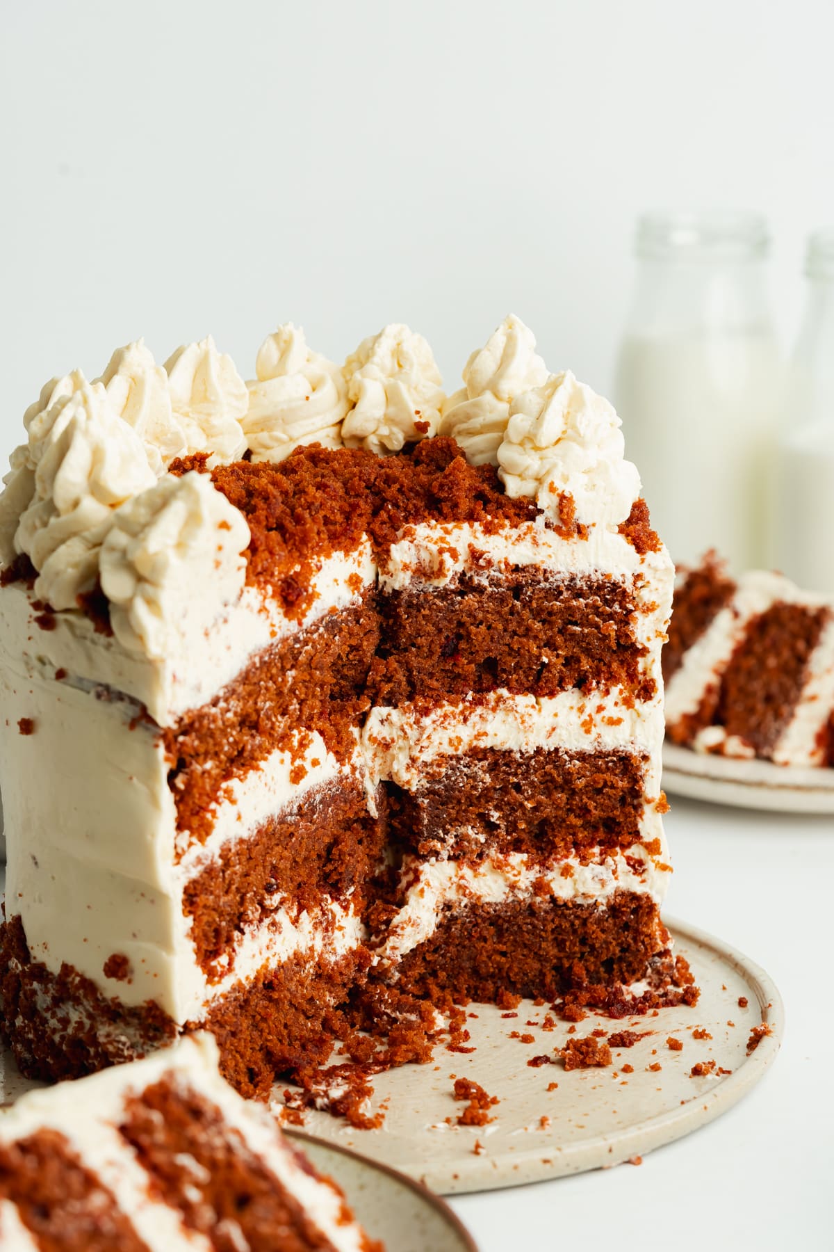 a red velvet layer cake with slices cut away showing the moist and light crumb.