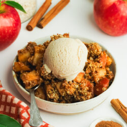 a bowl of apple crisp with a scoop of cinnamon vanilla ice cream on top.